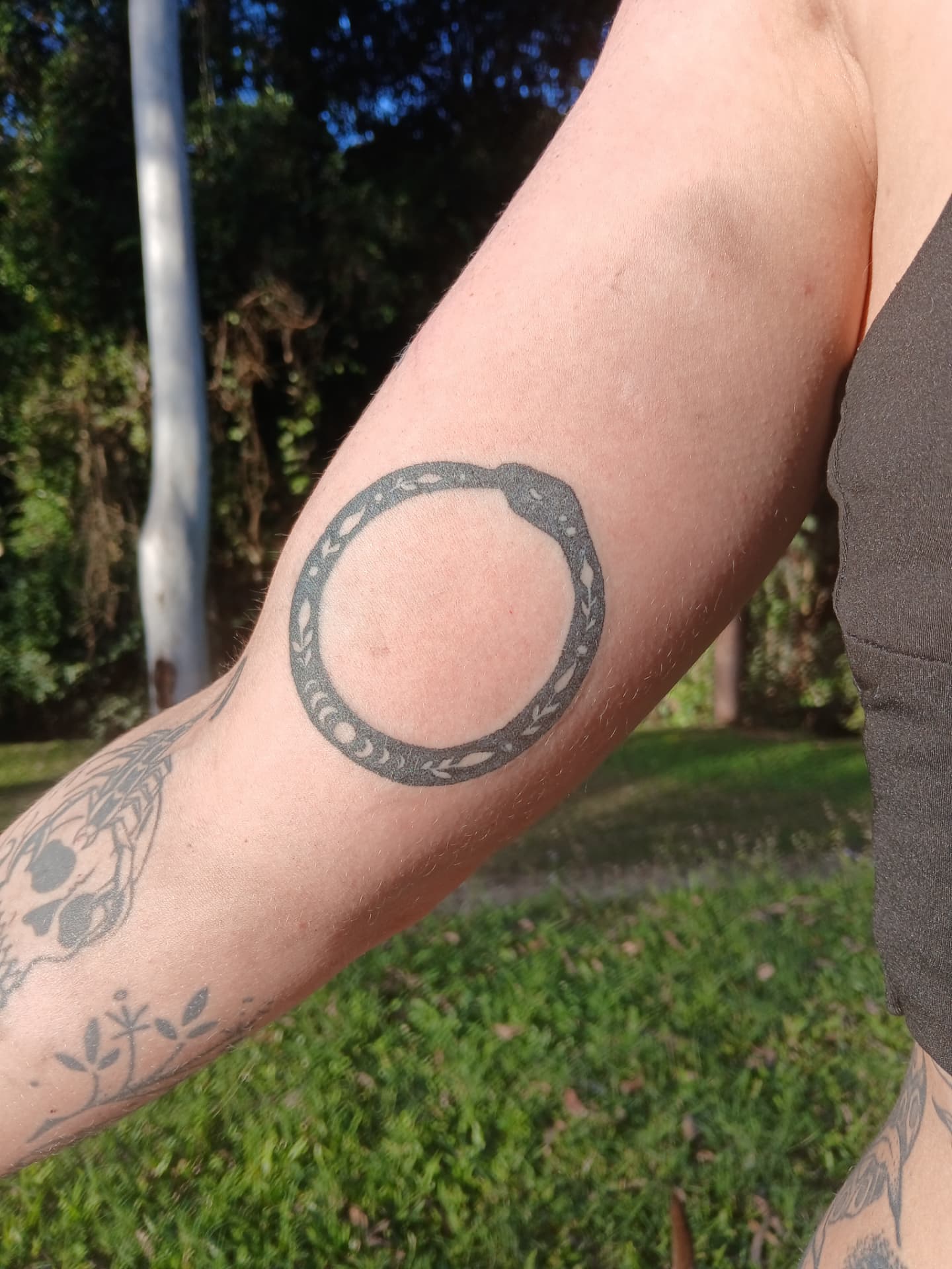 Ouroboros circle tattoo on inner arm