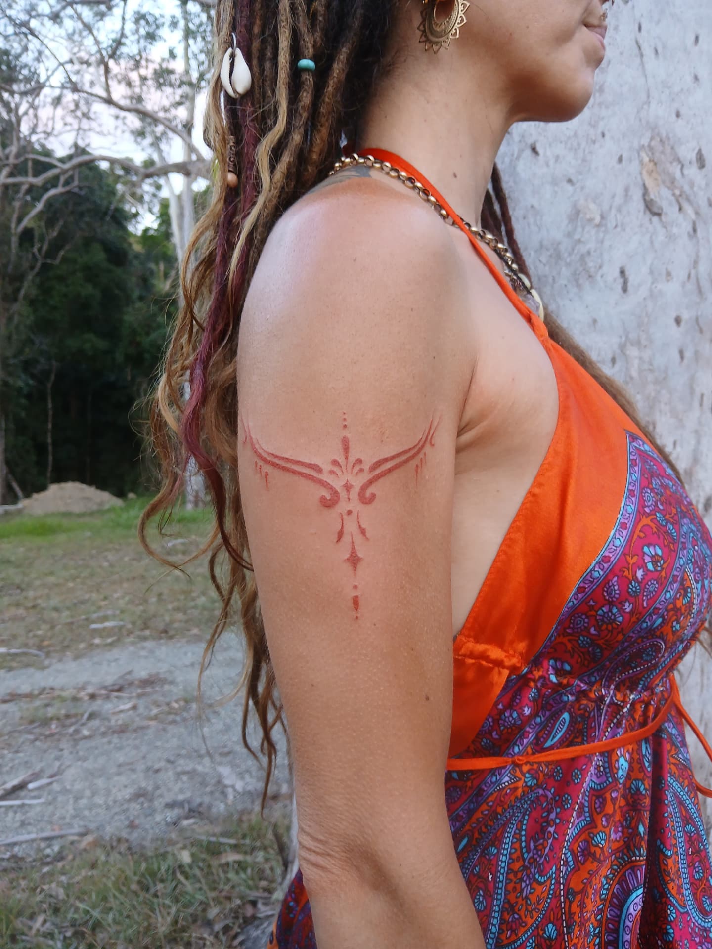 Red ink ornamental tattoo on shoulder